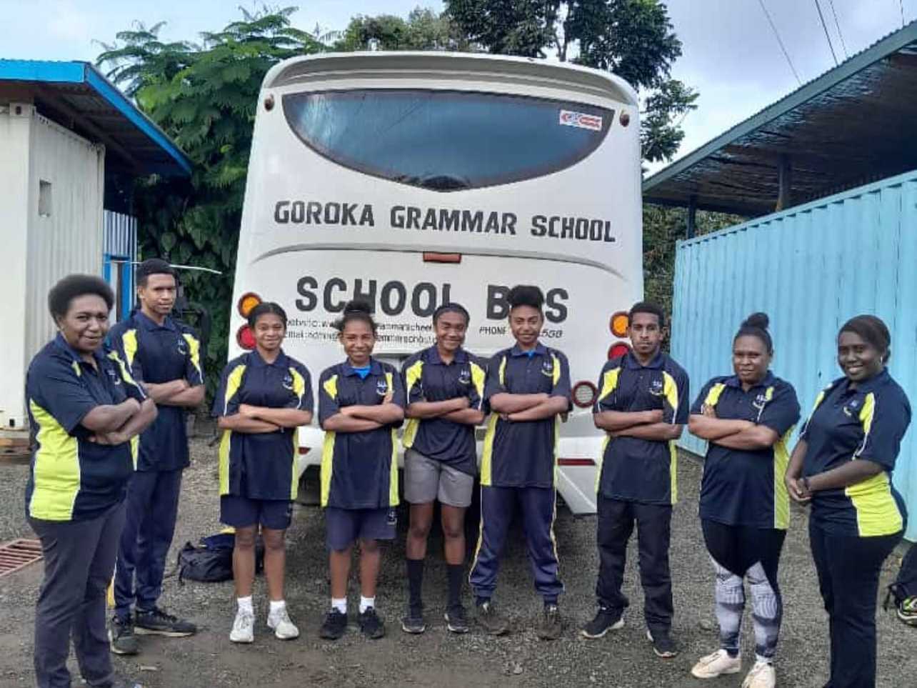 Boarding students and staff standing in front of the Goroka Grammar School bus.