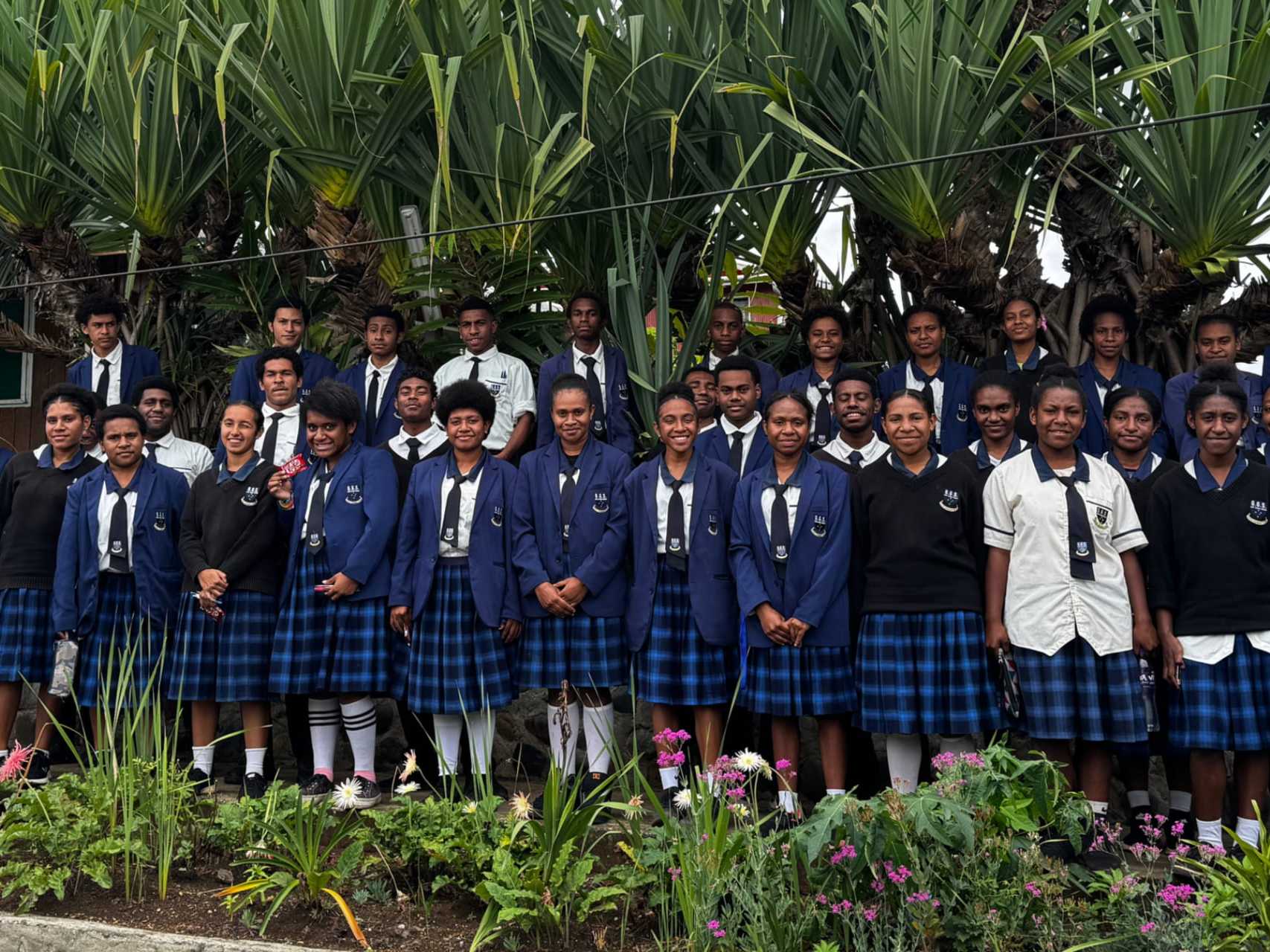 Secondary students in GGS blazers and kilts standing together in the school garden.